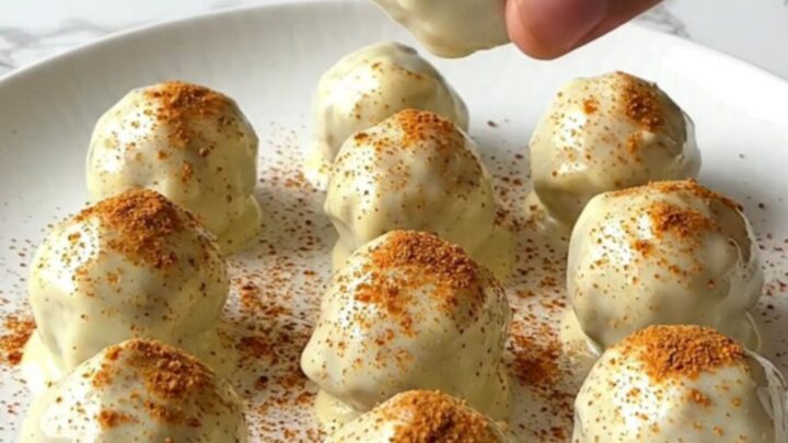 A plate of finished pumpkin pie truffles with a white chocolate coating and a light dusting of spice.