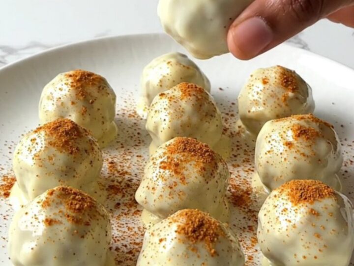 A plate of finished pumpkin pie truffles with a white chocolate coating and a light dusting of spice.