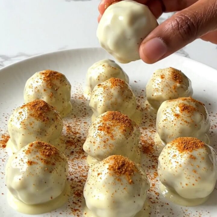 A plate of finished pumpkin pie truffles with a white chocolate coating and a light dusting of spice.