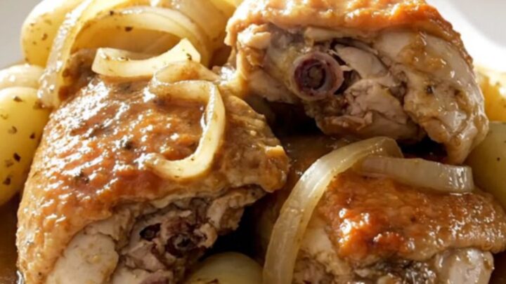 A top-down view of slow-cooked chicken thighs with tender potatoes and onions in a savory broth inside a black slow cooker.