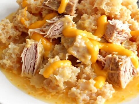 A close-up of a serving of cheesy ground turkey and hash brown casserole in a white bowl, showing creamy texture.