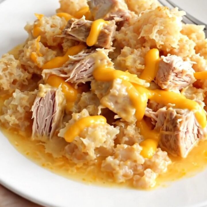 A close-up of a serving of cheesy ground turkey and hash brown casserole in a white bowl, showing creamy texture.