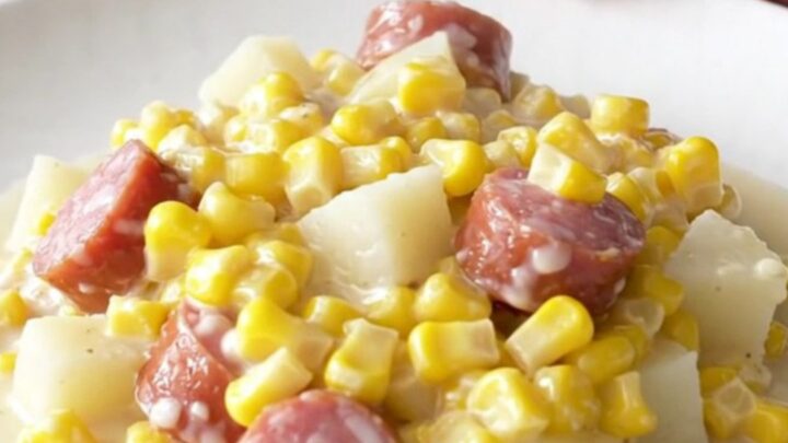 A close-up of a bowl filled with creamy sausage, tender potato cubes, and sweet creamed corn.