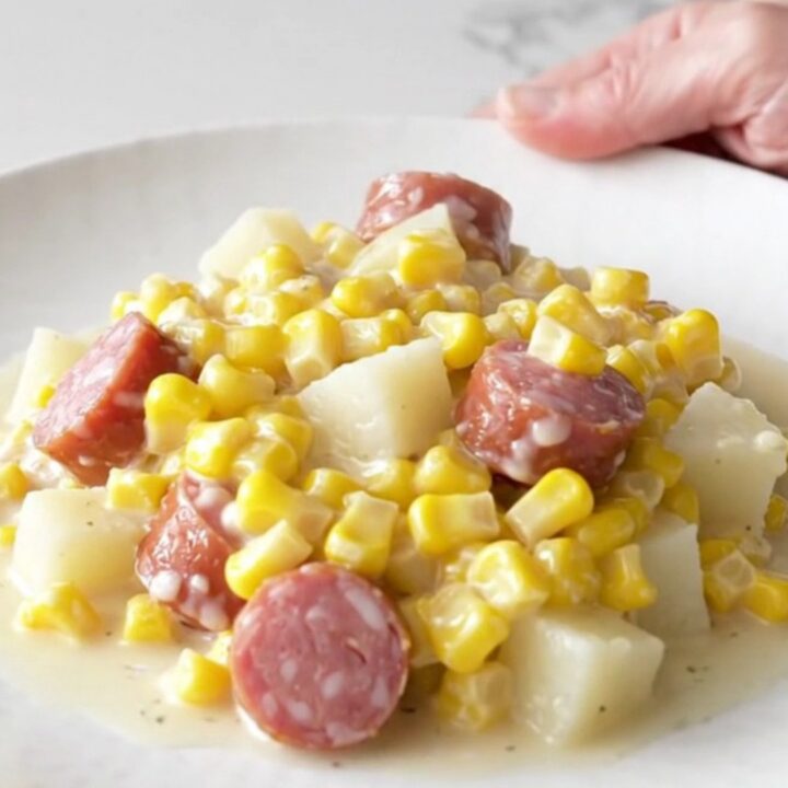 A close-up of a bowl filled with creamy sausage, tender potato cubes, and sweet creamed corn.