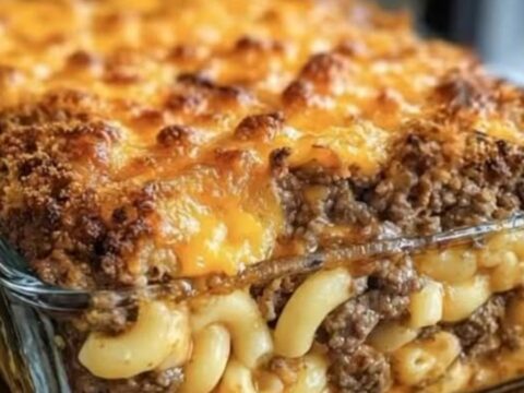 A close-up shot of a mac and cheese meatloaf casserole with a crispy golden crust and steaming layers.