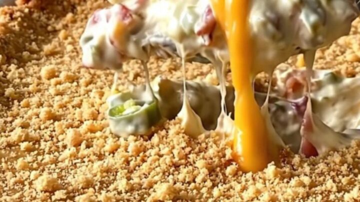 A top-down view of a rectangular ceramic dish filled with a creamy bacon and jalapeno dip topped with golden crackers.