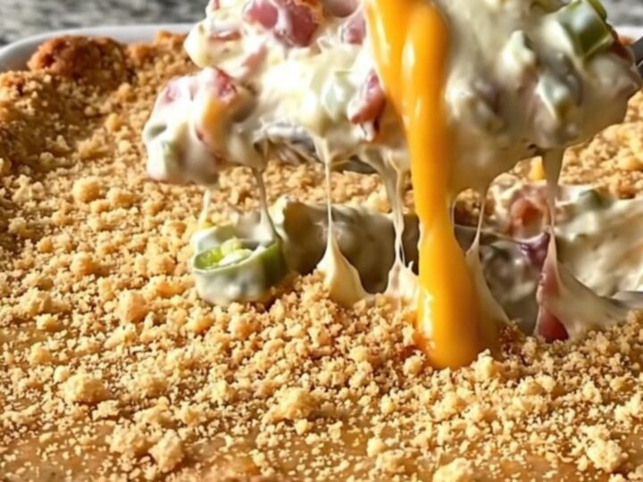 A top-down view of a rectangular ceramic dish filled with a creamy bacon and jalapeno dip topped with golden crackers.