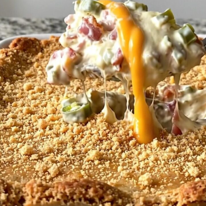A top-down view of a rectangular ceramic dish filled with a creamy bacon and jalapeno dip topped with golden crackers.