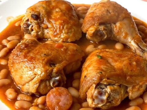Slow cooker chicken cassoulet with sausage and beans in a black ceramic insert.