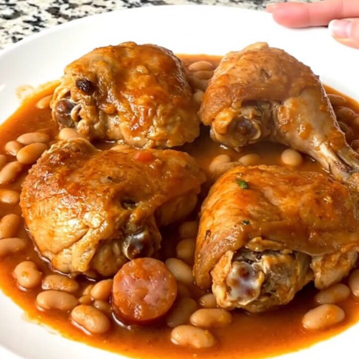 Slow cooker chicken cassoulet with sausage and beans in a black ceramic insert.