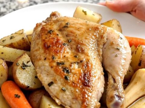 A black slow cooker filled with tender chicken breasts and chunks of carrots, parsnips, and potatoes.