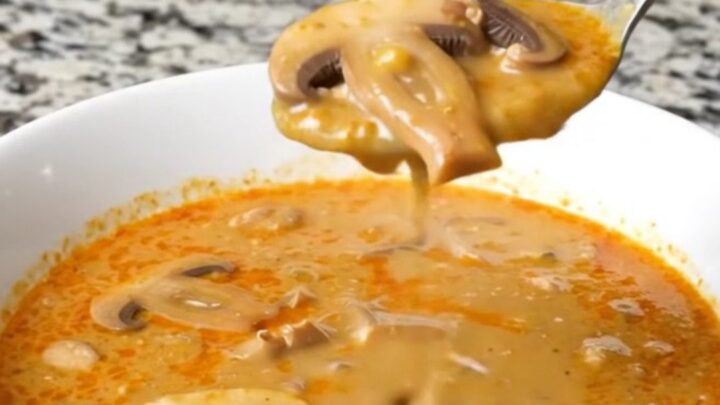 A steaming bowl of creamy Hungarian mushroom soup garnished with fresh herbs in a bright, modern kitchen.