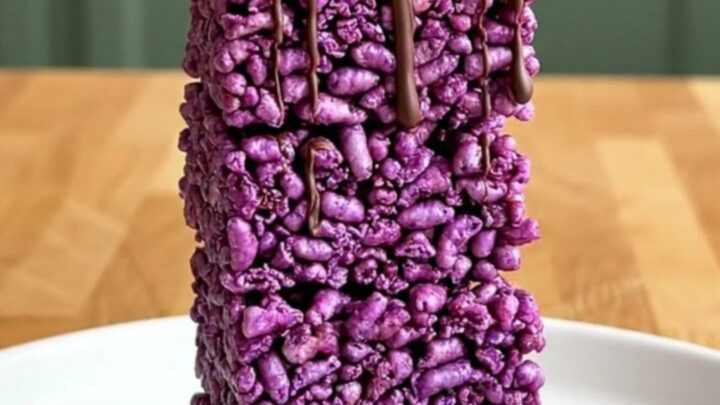 A top-down view of purple crispy rice squares on a parchment-lined baking sheet