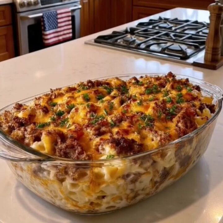 A close-up of a bubbling cheesy beef macaroni casserole in a glass dish with a golden crust.