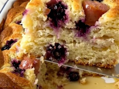 A golden, puffed blueberry and sausage breakfast pancake bake in a white enameled baker.