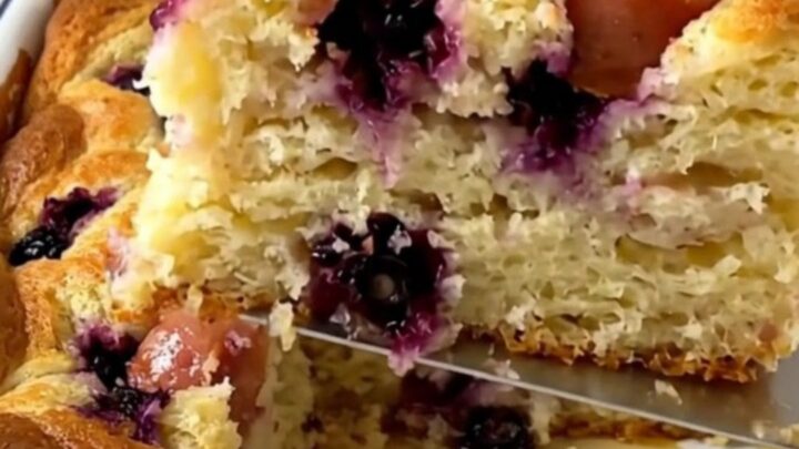 A golden, puffed blueberry and sausage breakfast pancake bake in a white enameled baker.