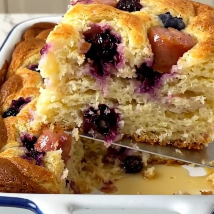 A golden, puffed blueberry and sausage breakfast pancake bake in a white enameled baker.