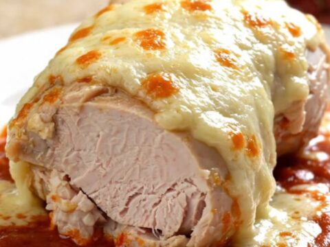 A close-up of tender, slow-cooked turkey breast topped with melted mozzarella and marinara sauce on a white plate.