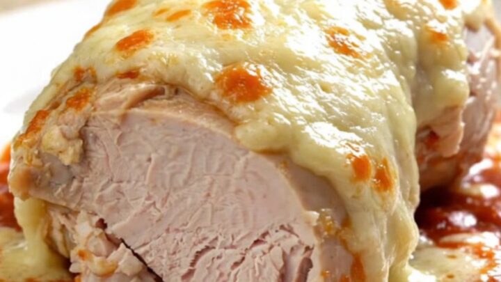 A close-up of tender, slow-cooked turkey breast topped with melted mozzarella and marinara sauce on a white plate.