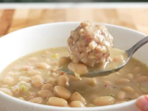 A bowl of creamy turkey meatball and white bean soup garnished with parmesan cheese.