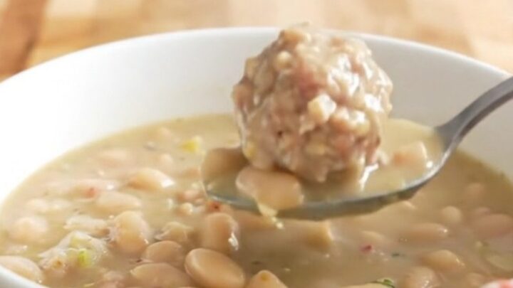 A bowl of creamy turkey meatball and white bean soup garnished with parmesan cheese.
