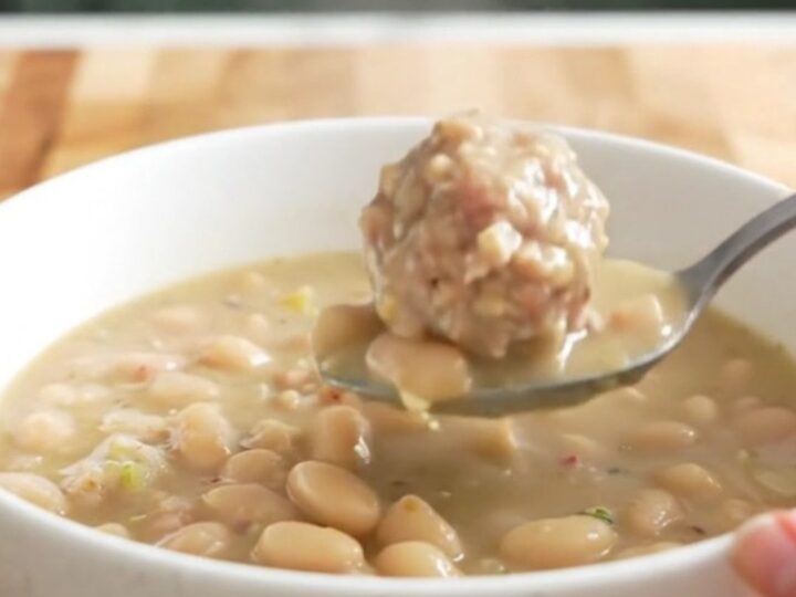 A bowl of creamy turkey meatball and white bean soup garnished with parmesan cheese.