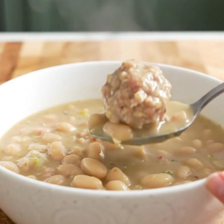 A bowl of creamy turkey meatball and white bean soup garnished with parmesan cheese.