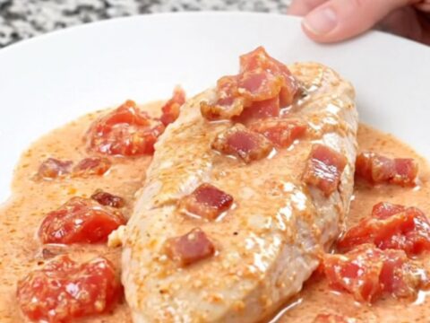 A plate of creamy BLT slow cooker chicken served with a rich, white sauce and bacon crumbles.