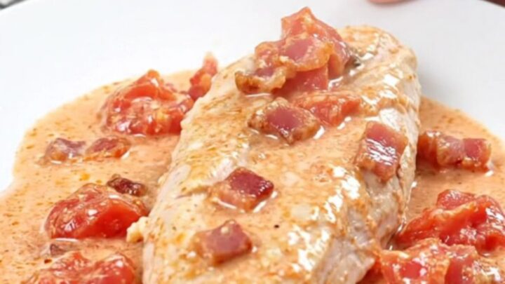 A plate of creamy BLT slow cooker chicken served with a rich, white sauce and bacon crumbles.
