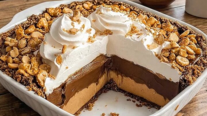 A dessert fork slicing through plush whipped cream, chocolate ganache, and peanut butter pie on a pretzel crust.