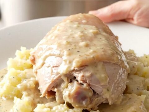 A slow cooker filled with turkey tenderloins, sliced potatoes, and onions in a creamy sauce.