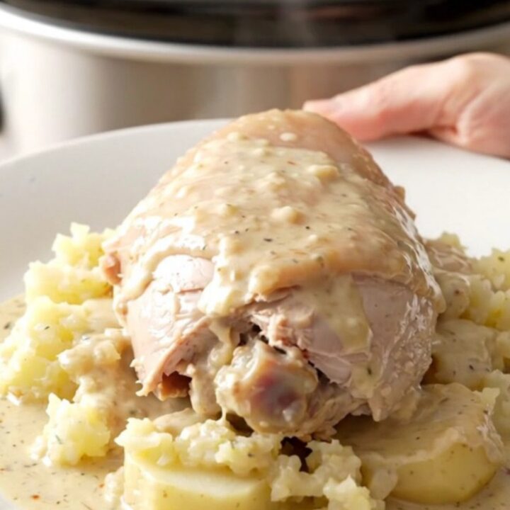 A slow cooker filled with turkey tenderloins, sliced potatoes, and onions in a creamy sauce.