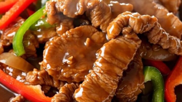A close-up of tender pork loin strips with bell peppers and onions in a rich brown sauce.