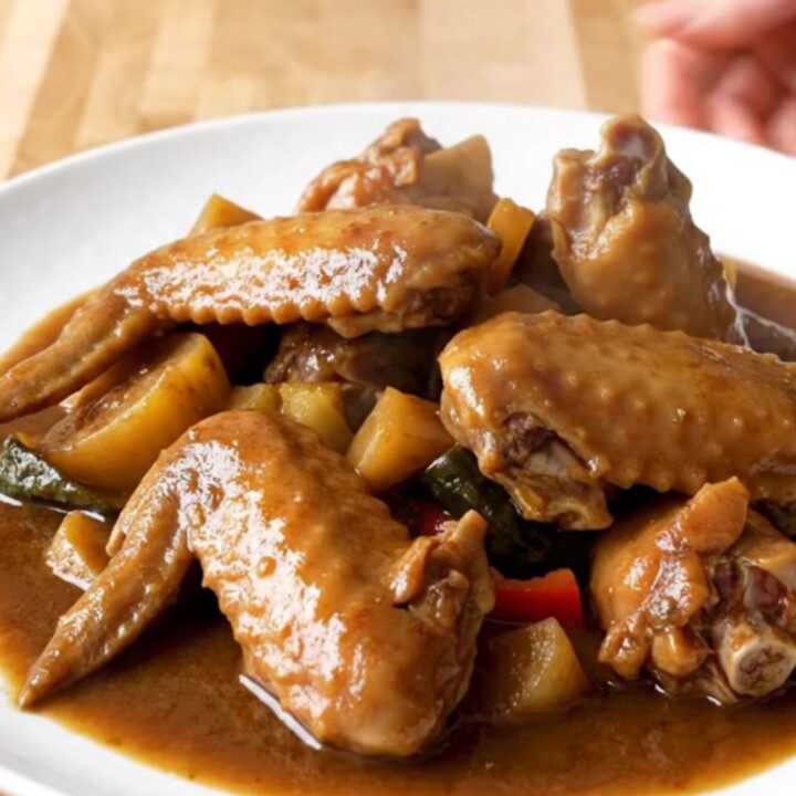 A close-up of tender Jamaican brown stew turkey wings served in a rich dark gravy.