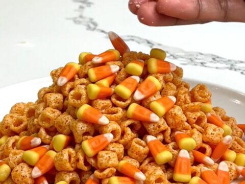 A close-up of Pumpkin Spice Muddy Buddies served on a white plate with a blurred kitchen background.