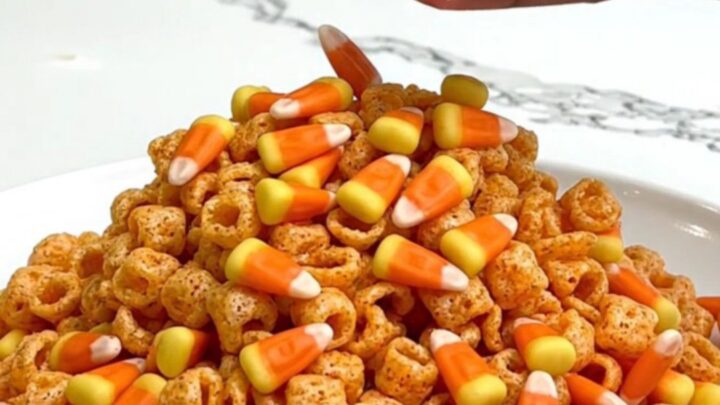 A close-up of Pumpkin Spice Muddy Buddies served on a white plate with a blurred kitchen background.