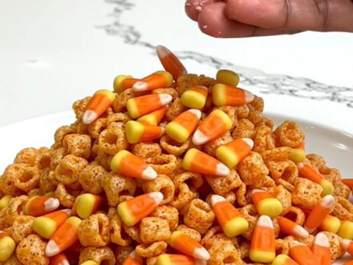 A close-up of Pumpkin Spice Muddy Buddies served on a white plate with a blurred kitchen background.