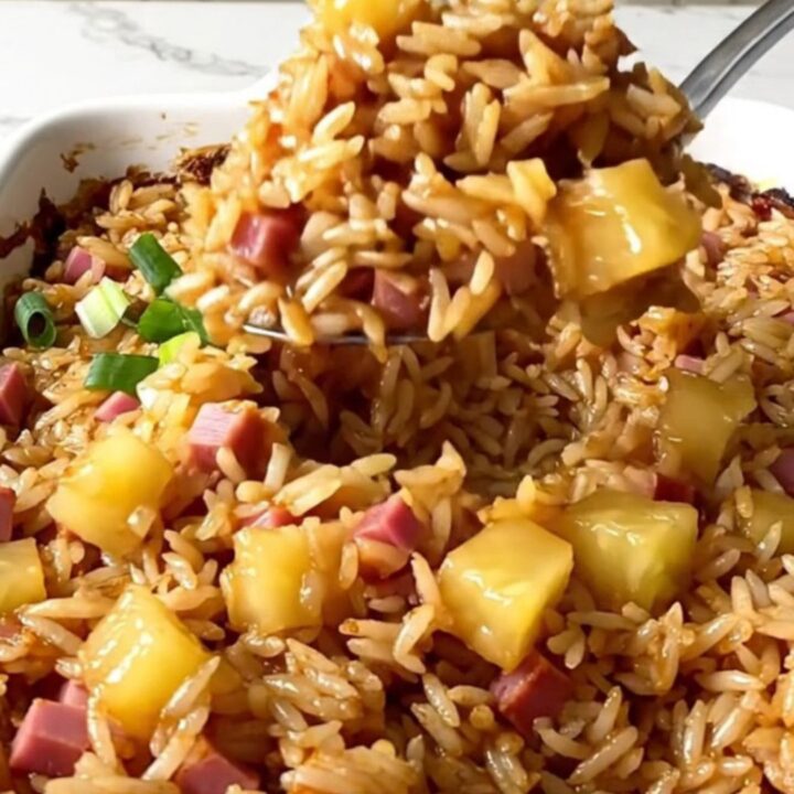 A top-down view of a rectangular baking dish filled with rice, ham, and pineapple pieces.