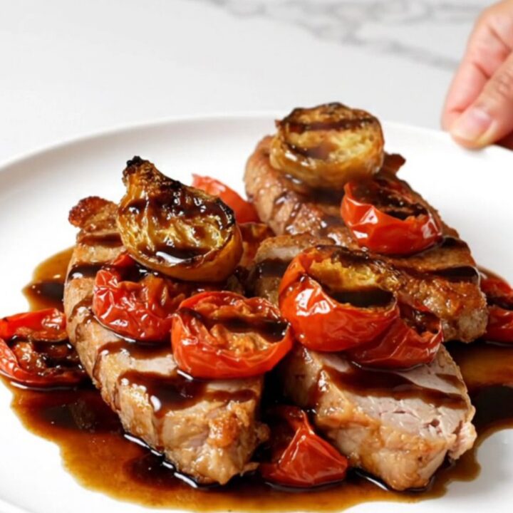 A close-up of slow-cooked turkey tenderloins topped with a balsamic tomato sauce on a white plate.