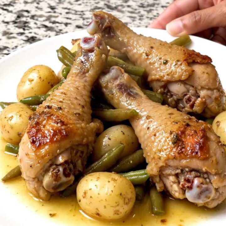 A rustic arrangement of braised chicken drumsticks, green beans, and baby potatoes in a slow cooker.