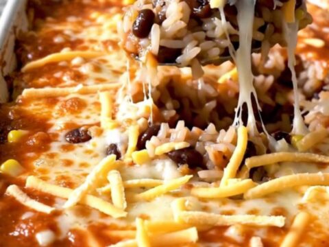 A top-down view of a rectangular baking dish filled with a layered black bean and rice enchilada bake.