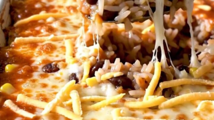 A top-down view of a rectangular baking dish filled with a layered black bean and rice enchilada bake.