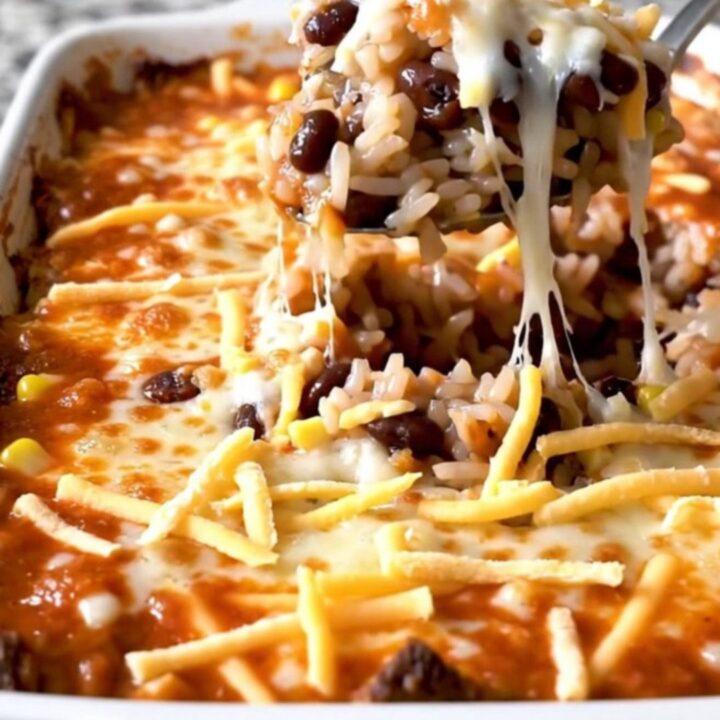A top-down view of a rectangular baking dish filled with a layered black bean and rice enchilada bake.