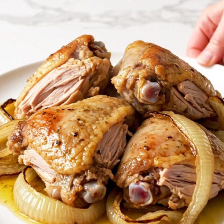 A top-down view of raw turkey thighs and red onion wedges inside a slow cooker, seasoned with colorful spices.