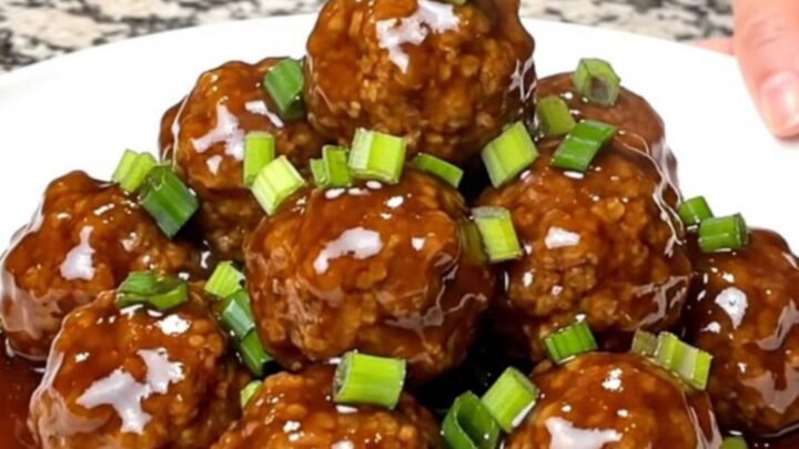 A close-up of tender turkey meatballs coated in a glossy hoisin sauce served on a white plate.