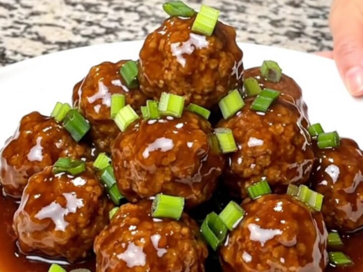 A close-up of tender turkey meatballs coated in a glossy hoisin sauce served on a white plate.