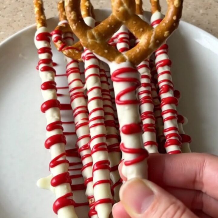 A plate of bloody vampire pretzel rods with white chocolate and red drizzle.