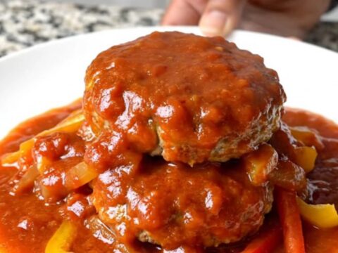A top-down view of raw turkey patties arranged in a ring inside a black slow cooker insert.