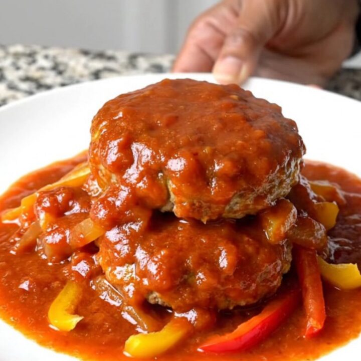 A top-down view of raw turkey patties arranged in a ring inside a black slow cooker insert.