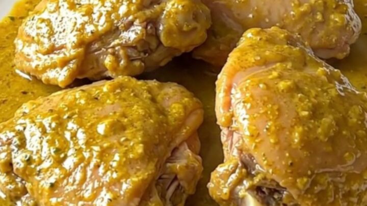 A high-angle shot of raw turkey thighs and cubed sweet potatoes in a slow cooker crock with coconut milk.
